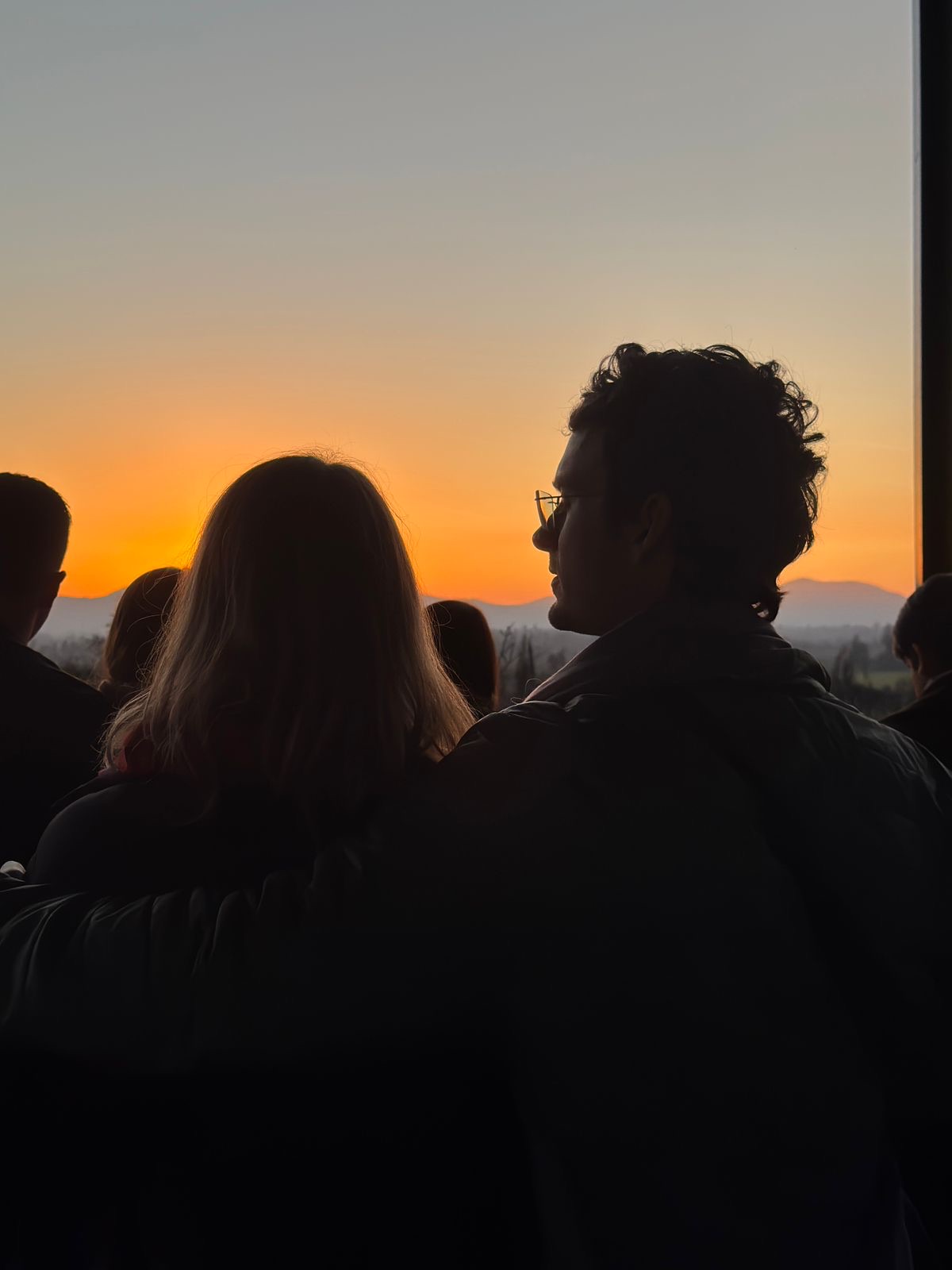 Rafaela e Lukas abraçados observando o pôr do sol