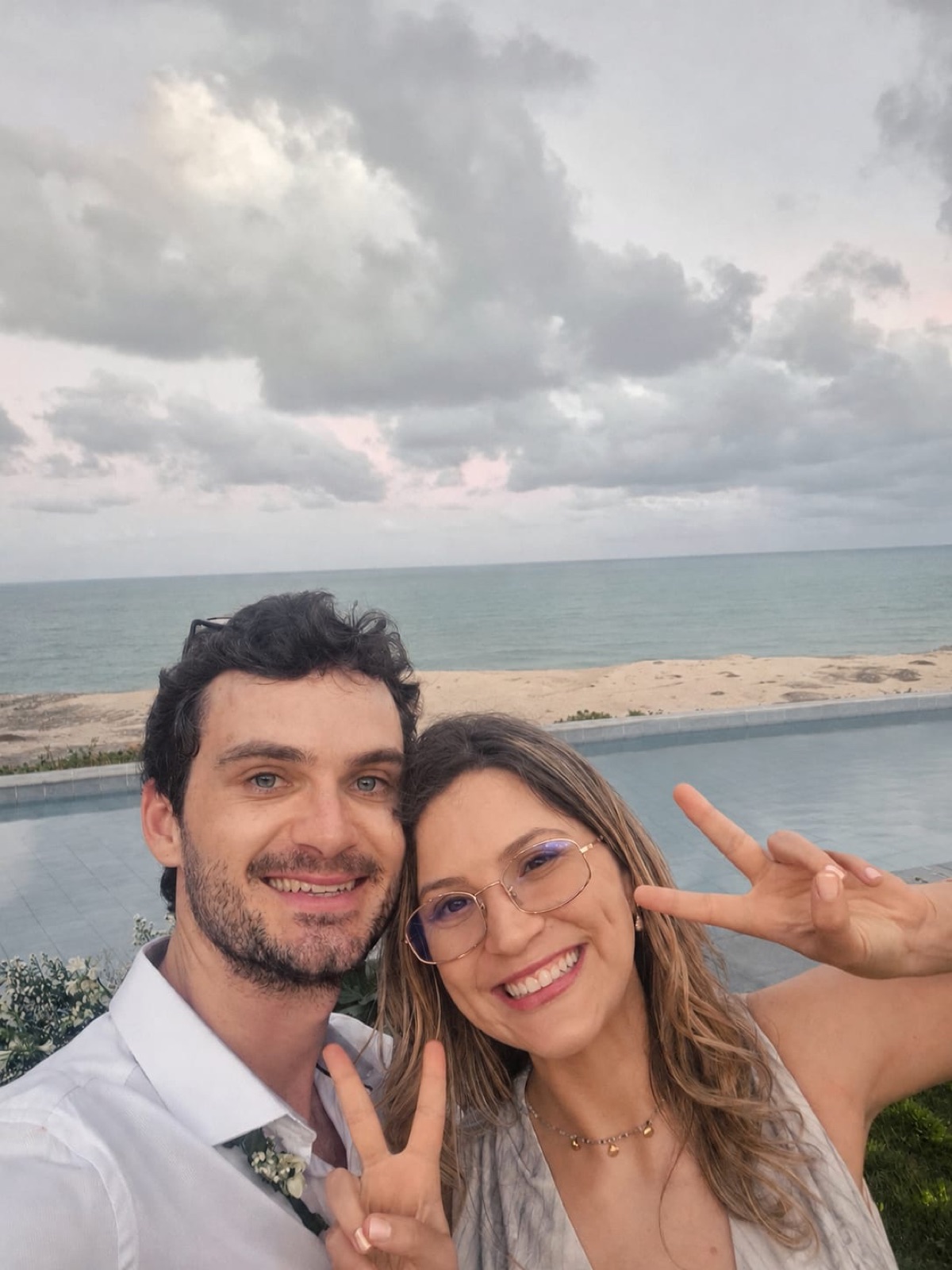 Casal na praia fazendo sinal de paz